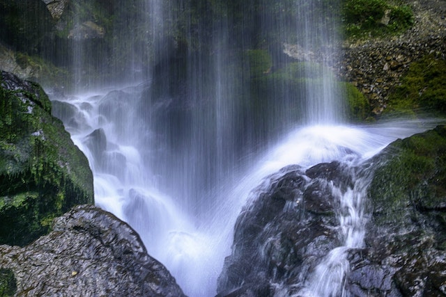 the base of a waterfall hitting moss-covered rocks below